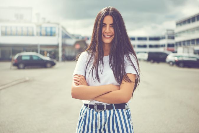 Brunette female smiling in striped trousers with arms crossed