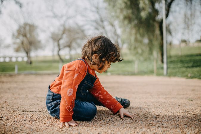 Child in overalls sitting outside