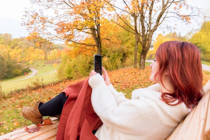 Woman relaxing on park bench checking phone