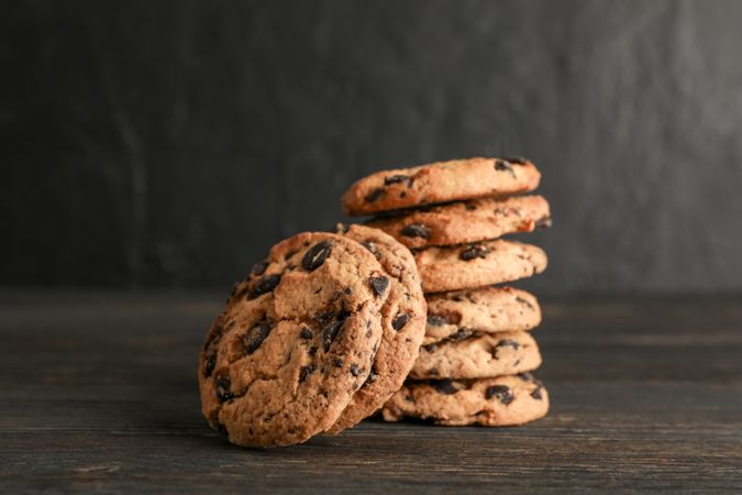 Stack of tasty chocolate chip cookies on wooden background. Space for text