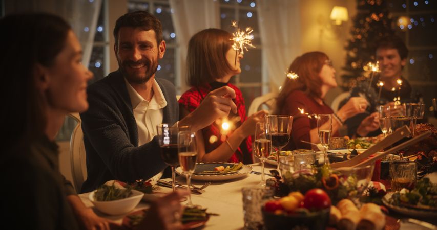 Parents, Children and Friends Enjoying Christmas Dinner Together in a Cozy Home in the Evening.
