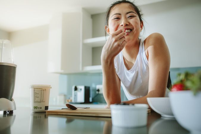 Healthy woman leaning to kitchen counter and smiling at home