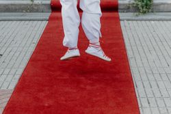 Person in gym shoes jumping on red carpet