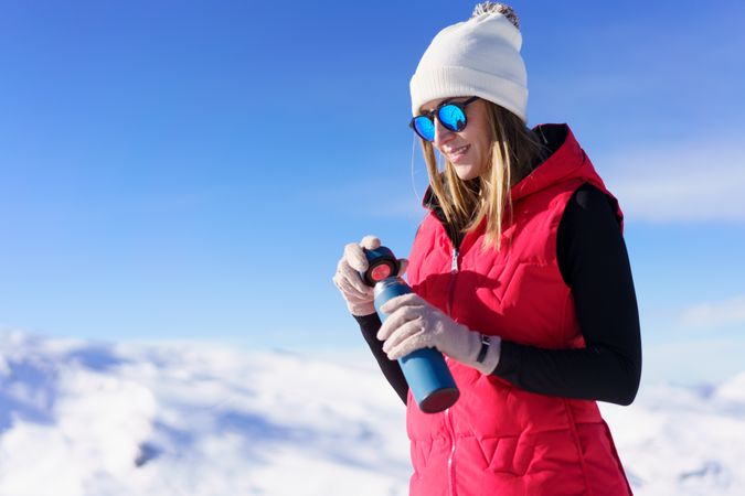 Woman in snowsuit with water bottle on snowy mountain