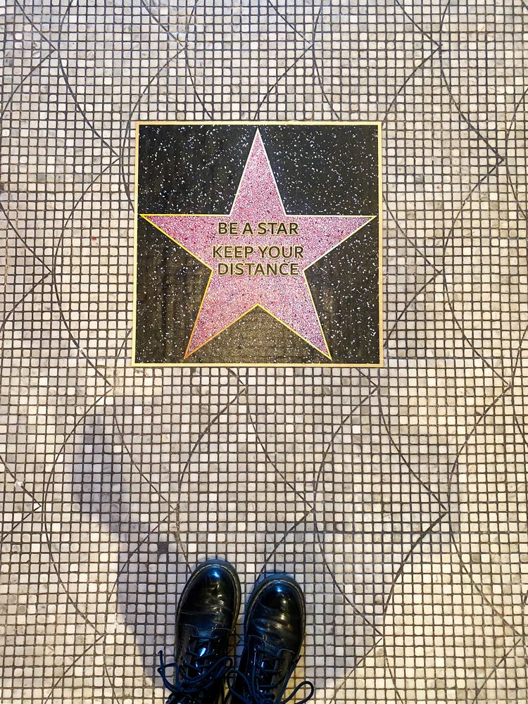 Floor sign resembling a Hollywood star asking for social distancing