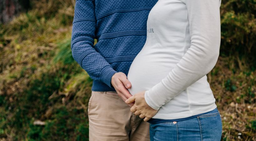 Pregnant woman with partner holding belly
