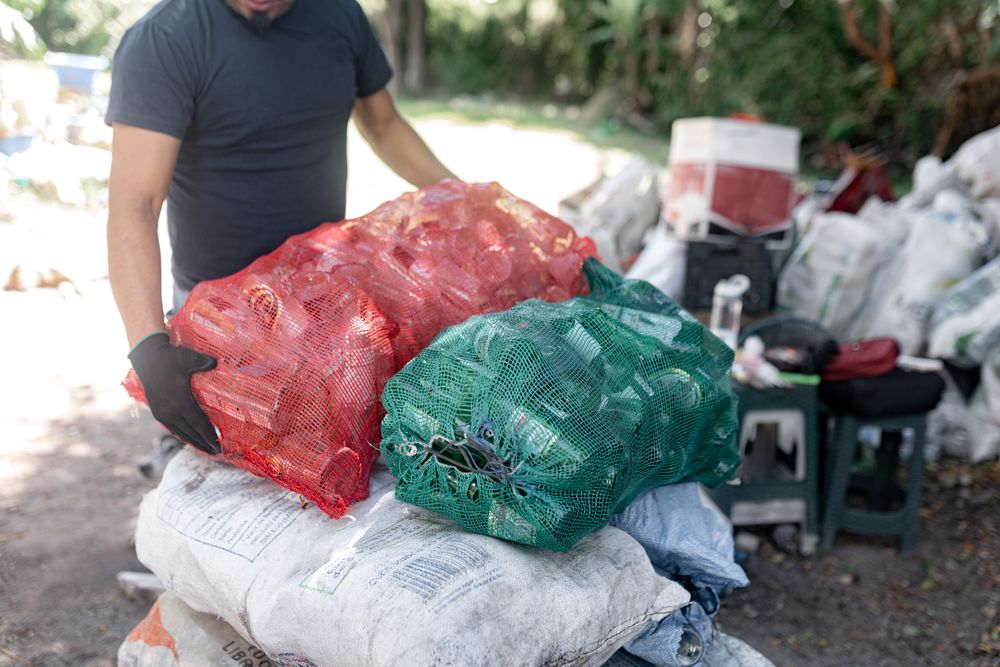 An Adult Hispanic Man is weighing Recycled Crystal Bottles. Close up