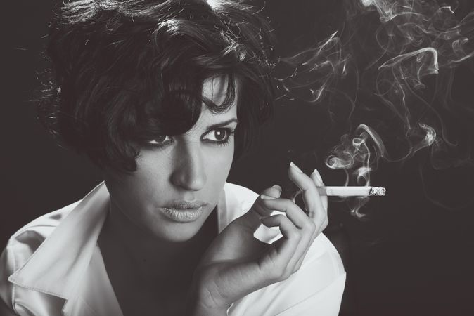 Woman smoking cigarette and looking away in monochrome