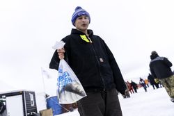 Nisswa, MN, USA - January 25th, 2020: A man holding a bag with a freshly caught fish