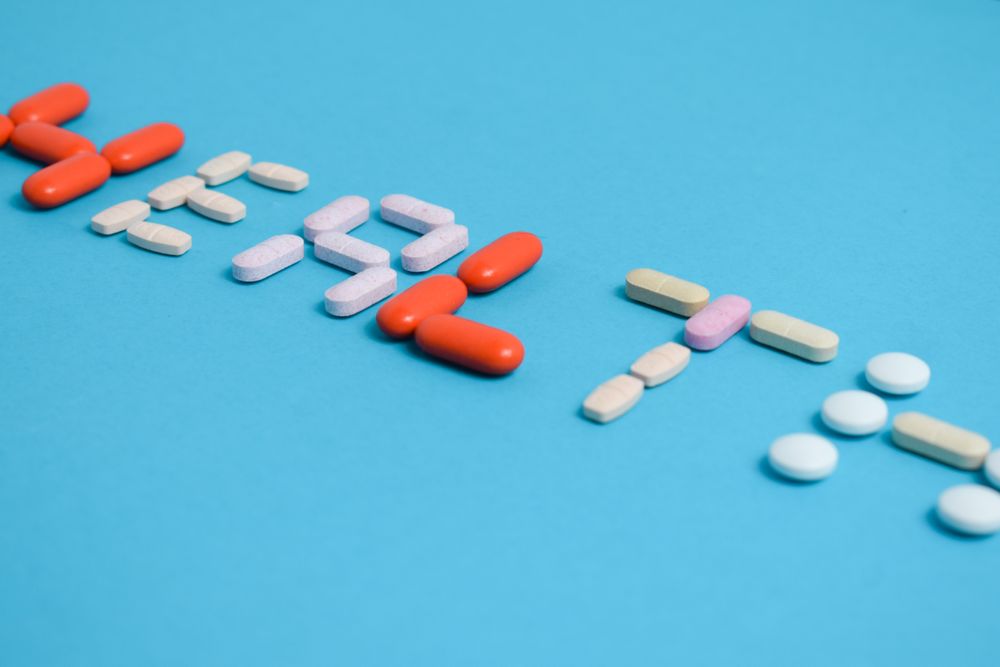 Multiple pills spelling the word "HEALTH" on blue table