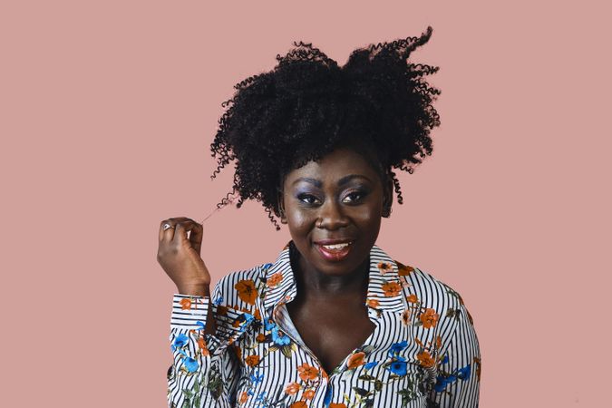 Portrait of Black woman with a hand playing with a curl