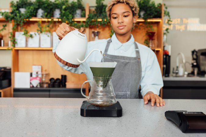 Black barista making pour over coffee in modern cafe