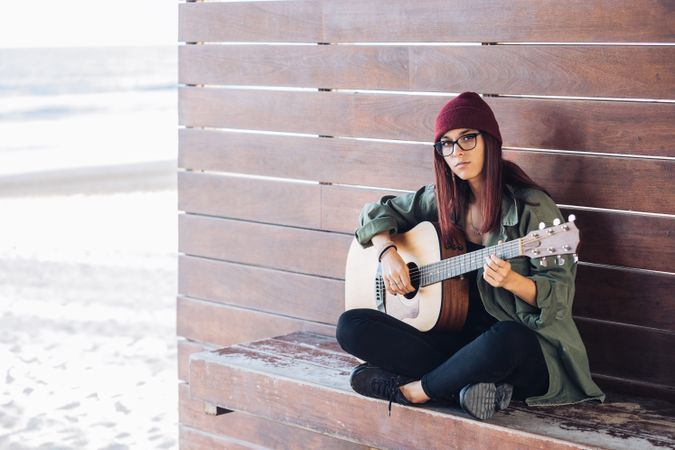 Romantic woman playing guitar leaning on wall
