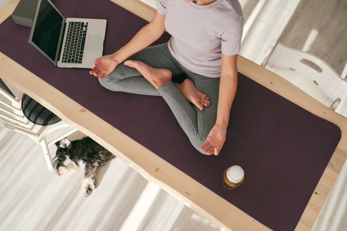 Unrecognizable woman practicing yoga with beer near laptop