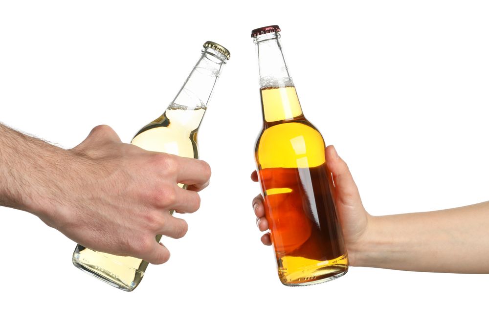 Hands hold bottles of cider, isolated on blank background. Cheers