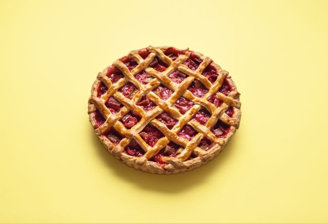 Strawberry and rhubarb pie isolated on yellow table