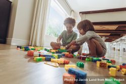 Two children sitting on floor and playing with building blocks 5oQqGb