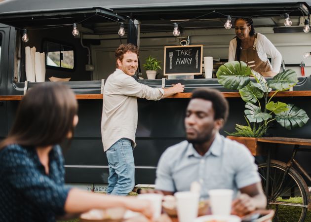 Multiracial people eating at food truck outdoor - Focus on center man face