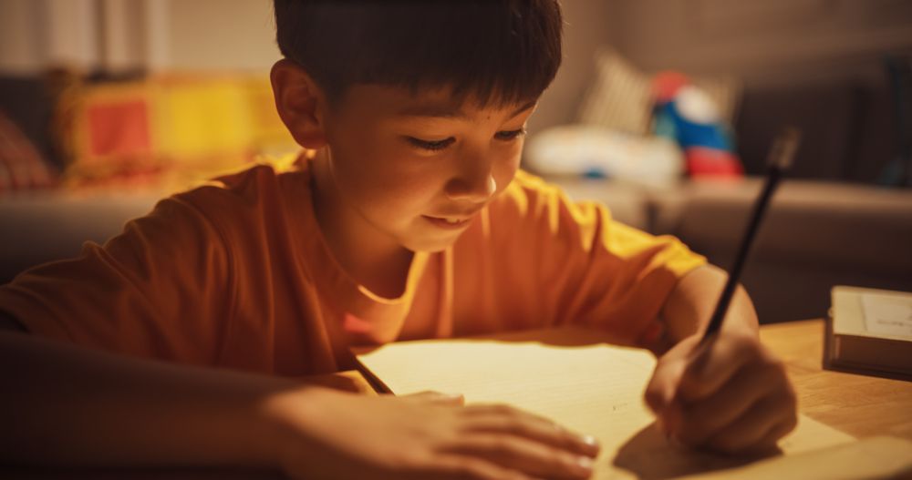 Evening Portrait of Smart Young Boy Doing Homework in the Living Room.