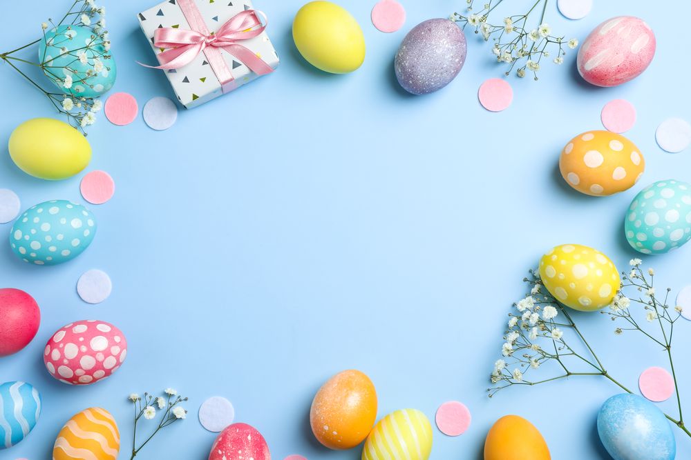 Flat lay composition with Easter eggs, present and flowers on color background, space for text. Top view
