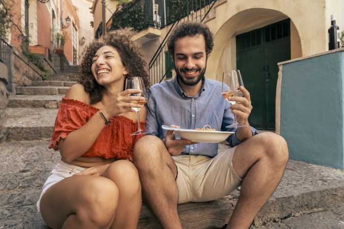 Young couple eating pasta and drinking wine in an Italian village