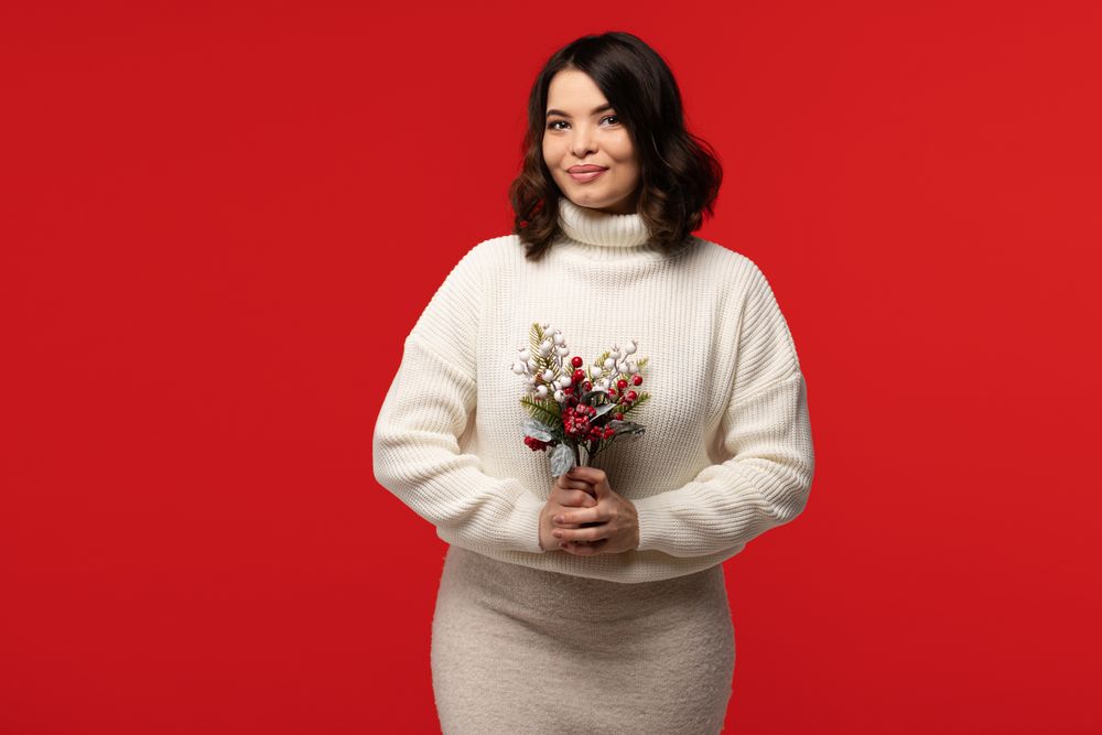 Charming woman in turtleneck holding festive bouquet.