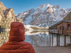 Unrecognizable person in warm jacket standing and looking at serene landscape