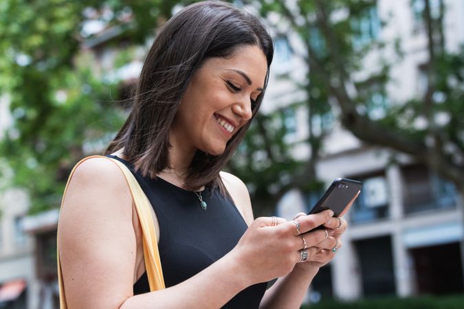 Smiling woman messaging on smartphone in city