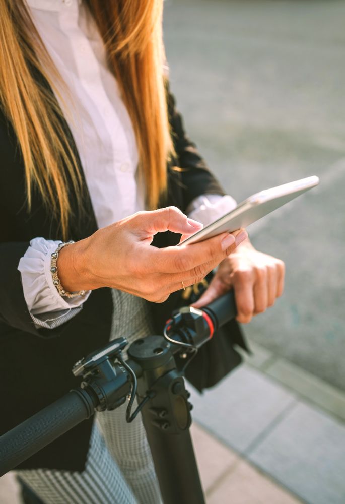 Detail of mobile of businesswoman with electric scooter