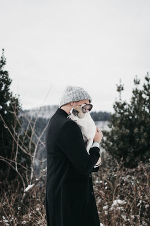 Young female hugging sad little dog in nature