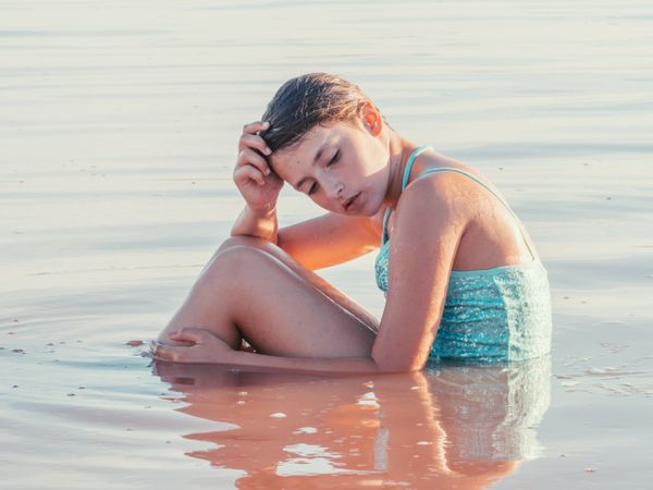 Teenage girl sitting in fresh water in sunny day
