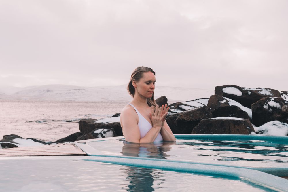 Woman sitting in pool near stones