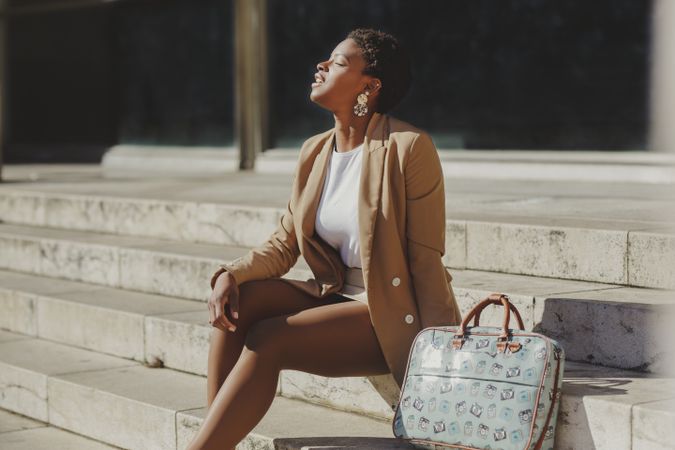 Stylish Black woman with handbag on steps on street
