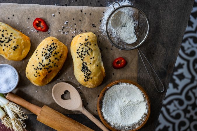 Top view of traditional Georgian pies with chicken meat, bell pepper and herbs, with flour and sieve 