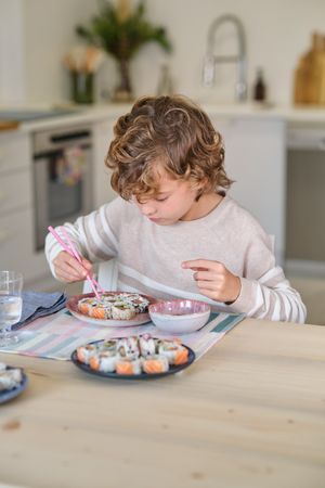 Kid eating delicious sushi at home