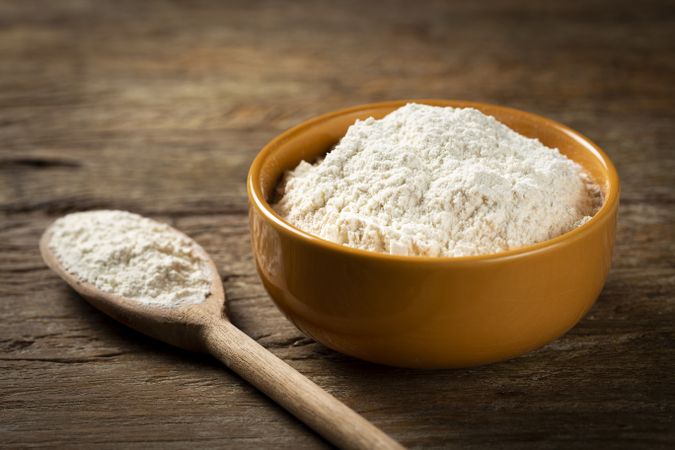 Bowl with wheat flour on the table.