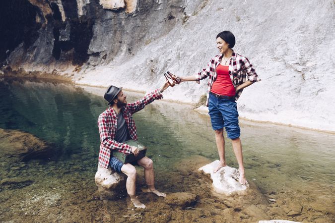 Couple clinking with beer chilling on lake