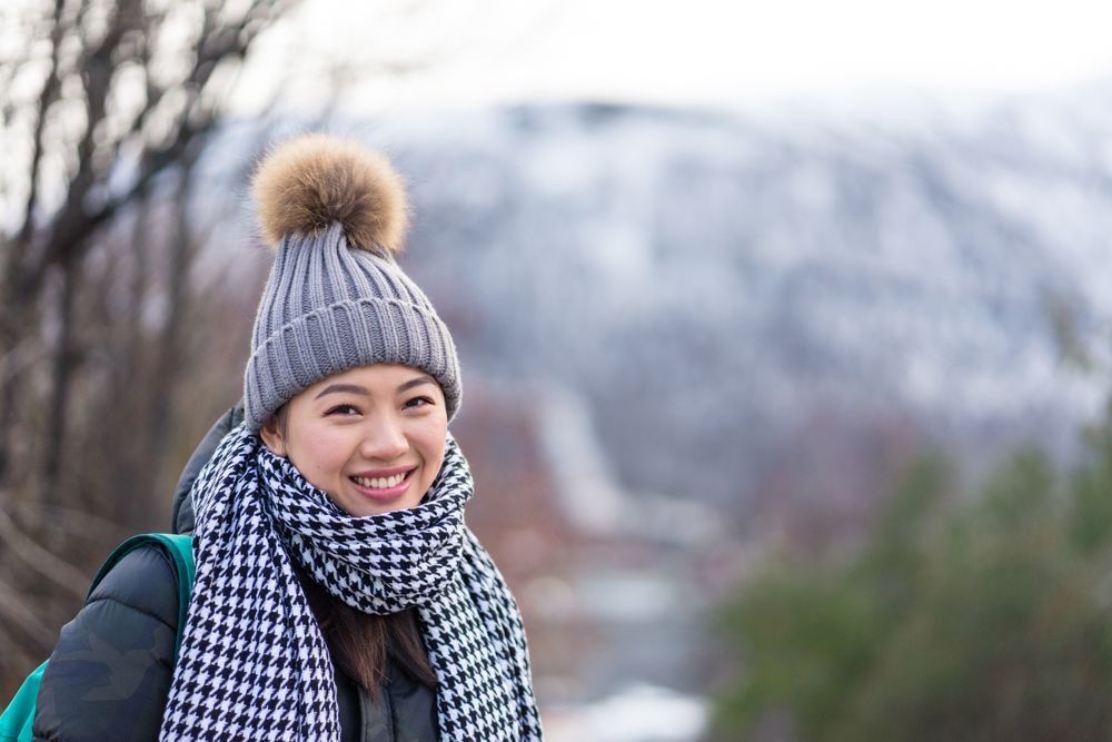 Asian female tourist in warm clothing at snowy nature