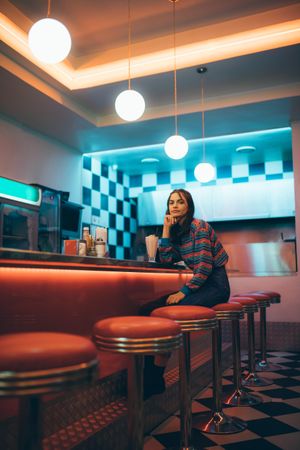 Attractive young woman sitting alone on bar stool