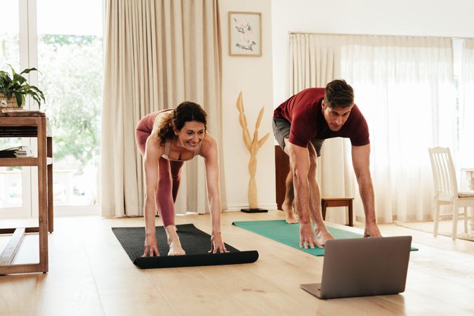 Couple exercising at home following instructions on laptop