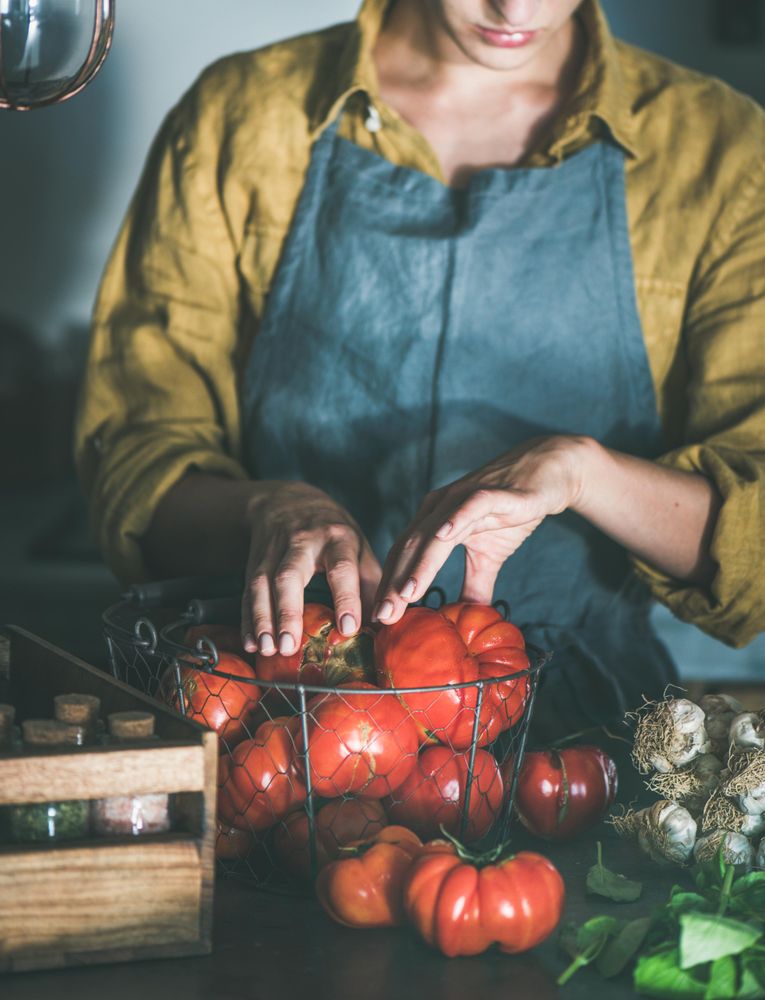Woman in yellow sorting tomatoes from wire basket