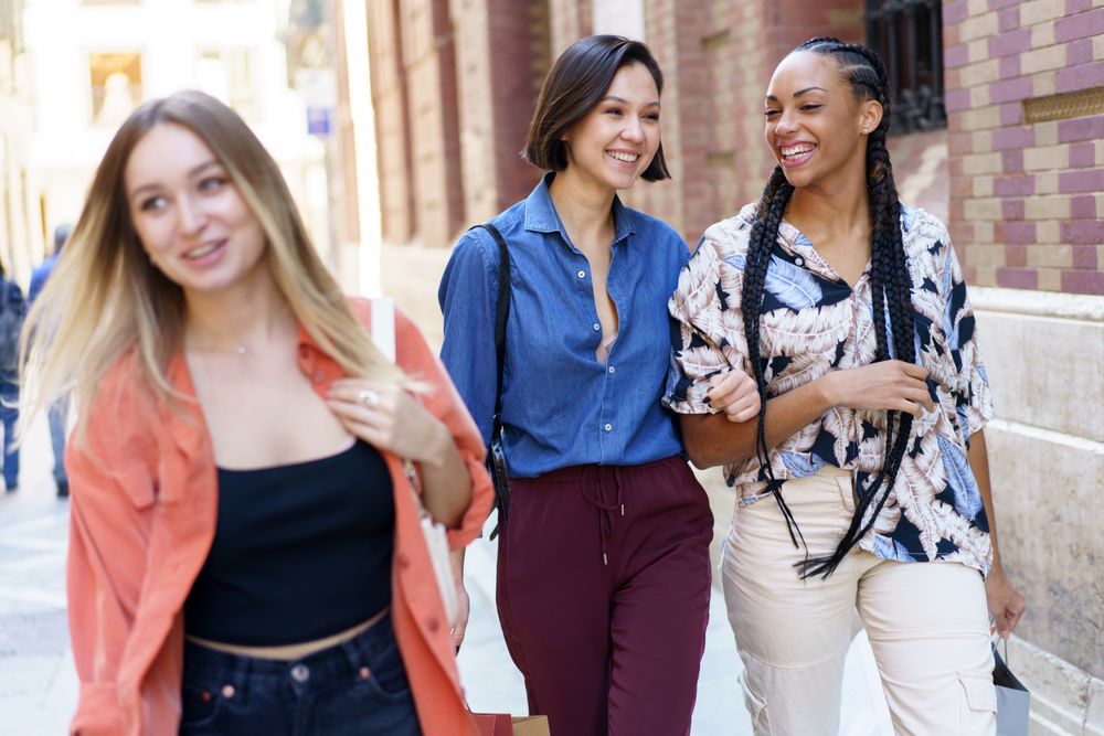 Women laughing together while walking down street with shopping bags