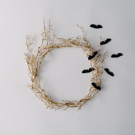 Thorny wreath made of branches on light background with bats