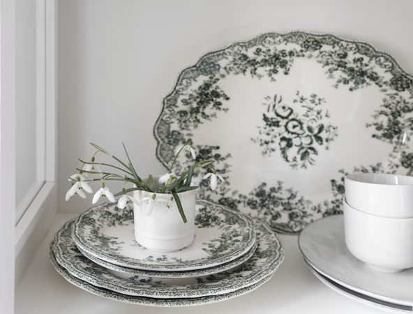 Snowdrop flowers in cup with green vintage floral plates dinnerware
