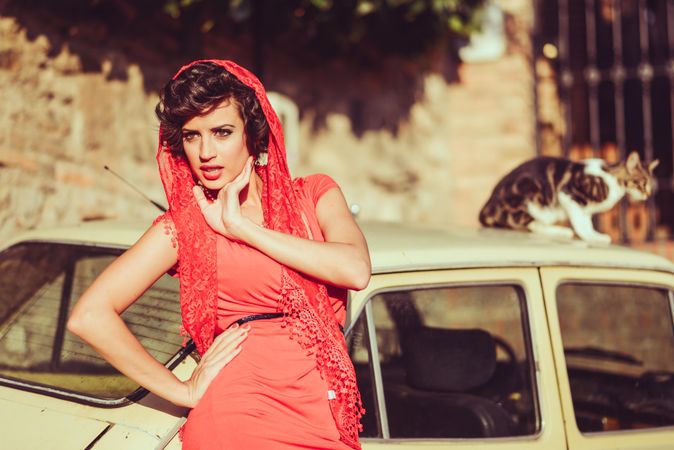 Elegant woman in dress standing by car in the sun