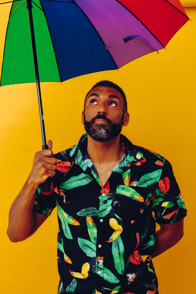 Black male looking up from under colorful umbrella