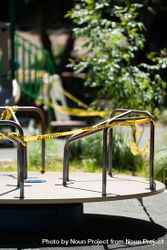 Closed caution signal tape around merry-go-round at city park 0V67X0