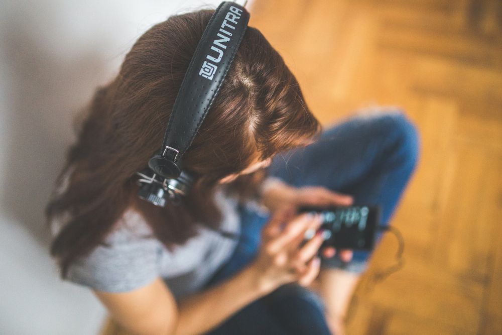 Top view of a woman wearing headphones and using smartphone