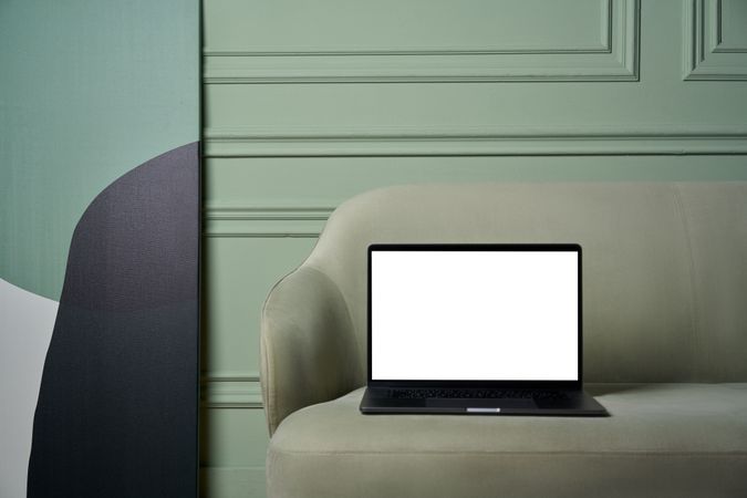 Blank laptop screen on gray couch indoor