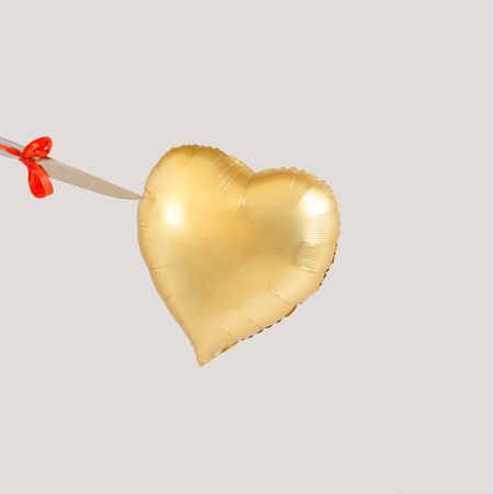 Gold heart balloon  being pierced with knife